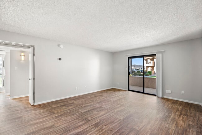 una sala de estar vacía con puerta corrediza de vidrio y balcón - Sundancer Apartments