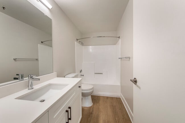 Renovated Package I bath with white quartz countertops, white cabinetry, and hard surface flooring