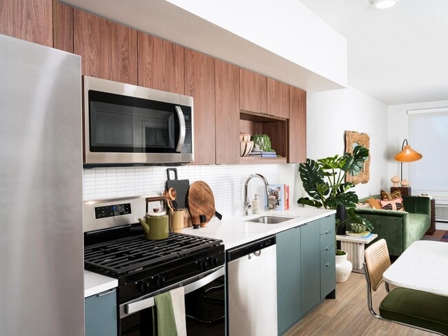 Nuestras cocinas gourmet cuentan con impresionantes encimeras de cuarzo, gabinetes personalizados e iluminación debajo de los gabinetes, creando el escenario perfecto para creaciones culinarias y entretenimiento. - Modera Raleigh Hills Apartamentos