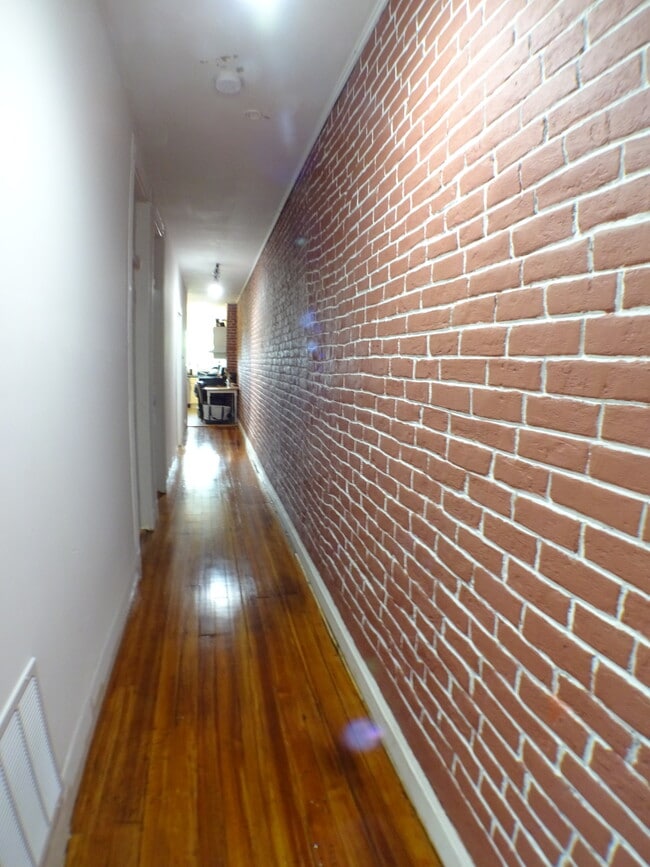 Long real brick but sealed so no dust hallway as you enter the apartment, the three bedrooms on on the left, each with a small closet and big enough for a queen bed, kitchen and baths at the end of this hallway...