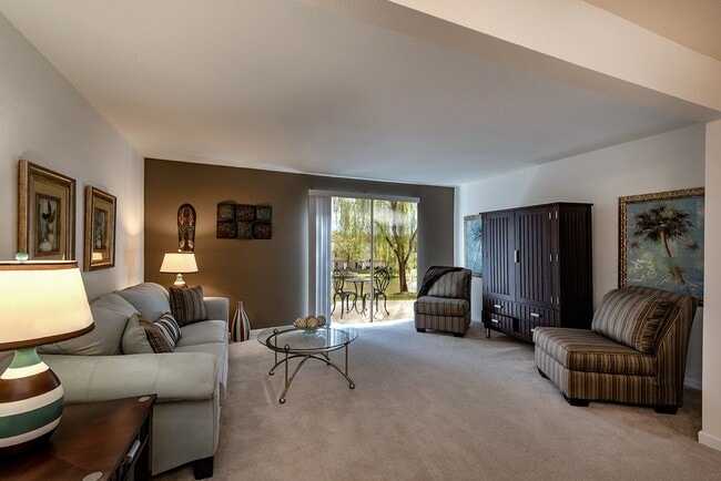 Spacious living room with private patio and view of the community pond - Shadowmoss Pointe Apartments and Townhomes