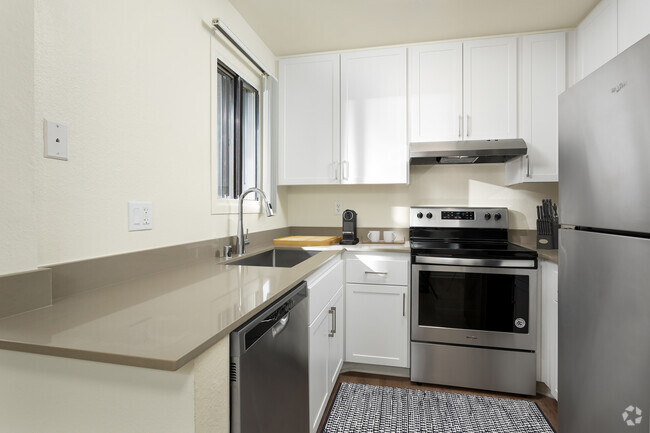 Renovated I kitchen with grey quartz countertops, white cabinetry, stainless steel appliances, and hard surface flooring - eaves Warner Center Rental