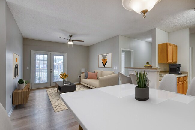 Dining Room looking into Living Room Dunwoody Place featuring large windows, light wood flooring, neutral tones, and a bright, comfortable layout in an affordable income-restricted apartment in Huntsville, AL. - Dunwoody Place