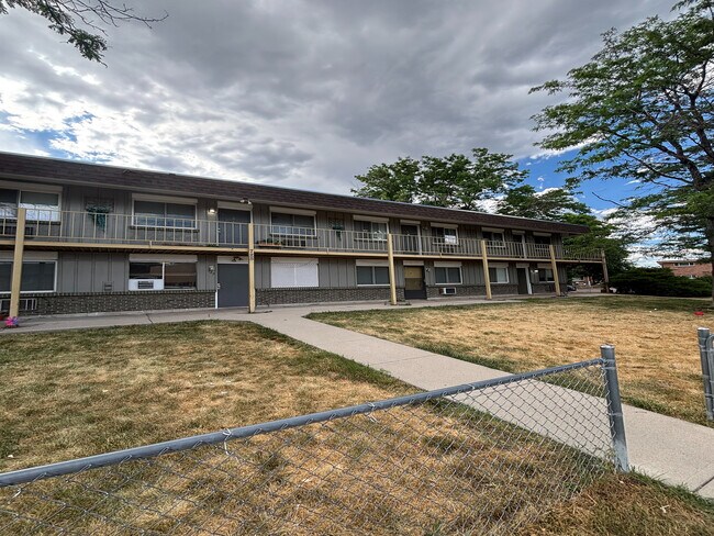 Charming two-story apartment complex with a spacious balcony, surrounded by lush greenery and a clear blue sky, offering a serene living environment. - Copperwood Apartments