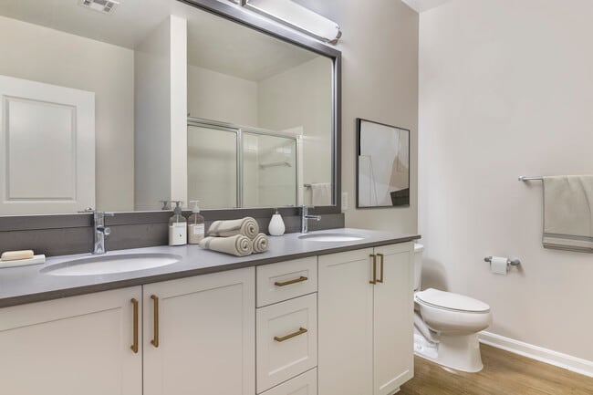 Renovated Package II bath with grey quartz countertops, white cabinetry, and hard surface flooring