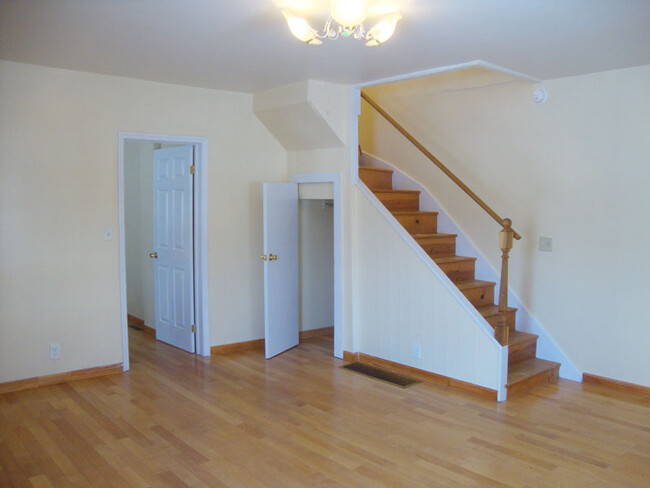 Living room with closet, entry to kitchen, and steps to second floor. - 239 W Venango St Apartments Unit A