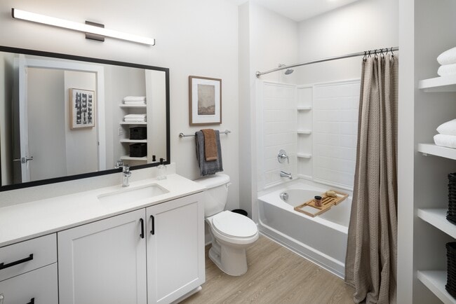Bath with white shaker cabinetry, white quartz countertops, and hard-surface vinyl place flooring