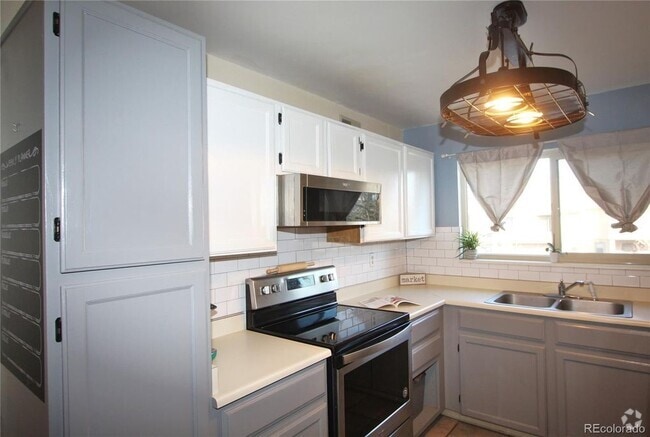Kitchen with lots of cabinets and natural light. Newer stainless range and microwave - 3656 S Depew St Unit 205 Rental