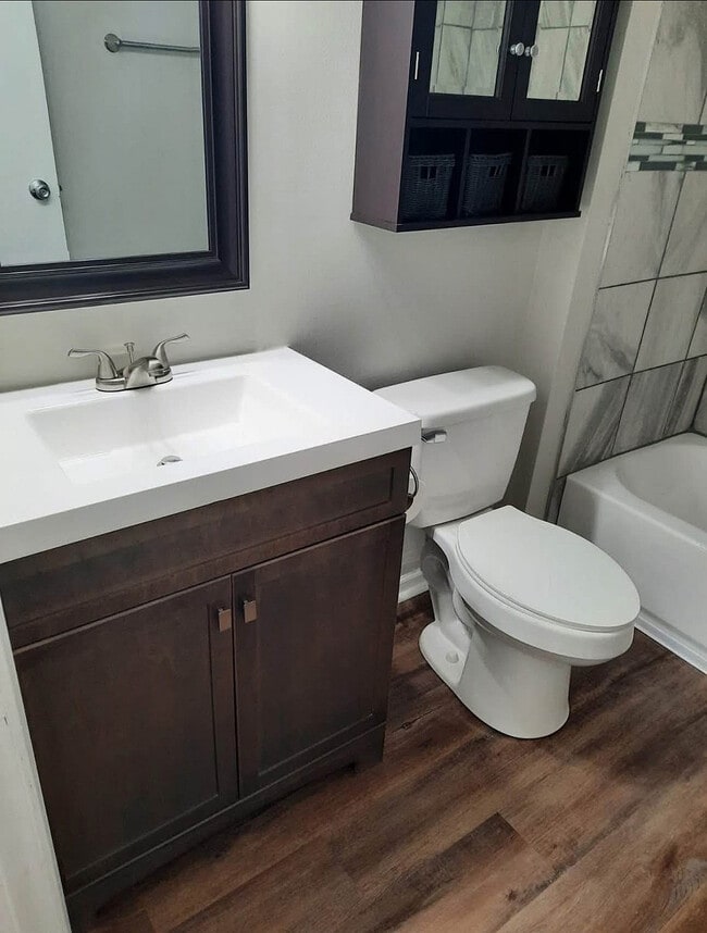 Modern bathroom with elegant dark wood vanity, sleek white countertop, and stylish tile accents.