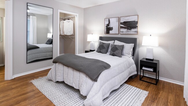 Unwind in a cozy bedroom featuring wood-style flooring, soft lighting, and a spacious walk-in closet. - The Enclave at Huntington Woods