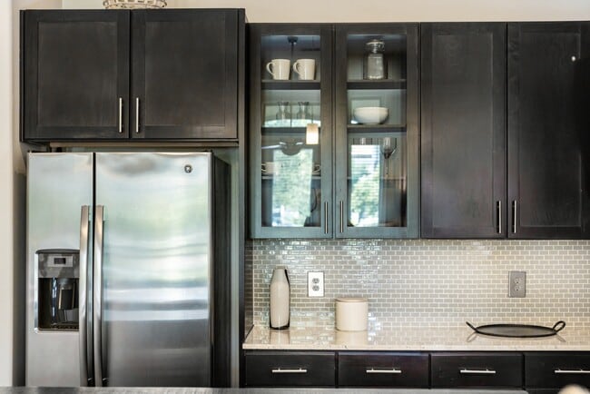 Kitchen with espresso cabinetry, granite countertops, tile backsplash, and stainless steel appliances - Avalon Lakeside