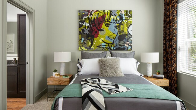 Spacious apartment bedroom with wood floors overlooking bathroom.