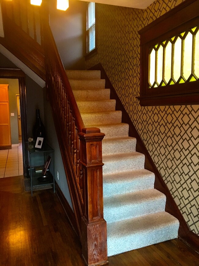 Historic stained glass window and refinished wood lead you up stairs to the second floor. - 565 Delta Avenue