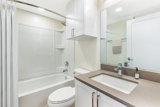 Renovated Package II bath with light grey quartz countertop, white shaker cabinetry, and hard surface flooring