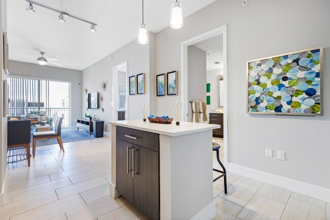 Model kitchen and dining room at our apartments in Boca Raton, featuring chairs around a table and counter seating.