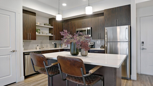 Large kitchen island with seating and modern pendant lighting. - Parkway Lofts