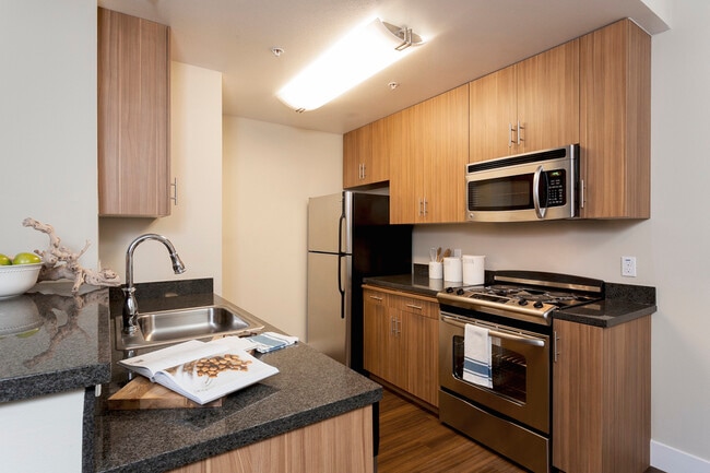 Classic Package III kitchen with stainless steel appliances, black speckled granite countertops, oak cabinetry, and hard surface flooring