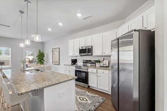 Spacious kitchen with an island, ample storage, stainless steel appliances and view into the backyard.