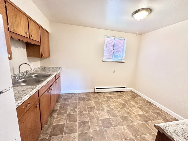 Bright, modern kitchen with sleek countertops, dual sink, and elegant wood cabinets; perfect for culinary creativity. - 7250-7290 Newton Street