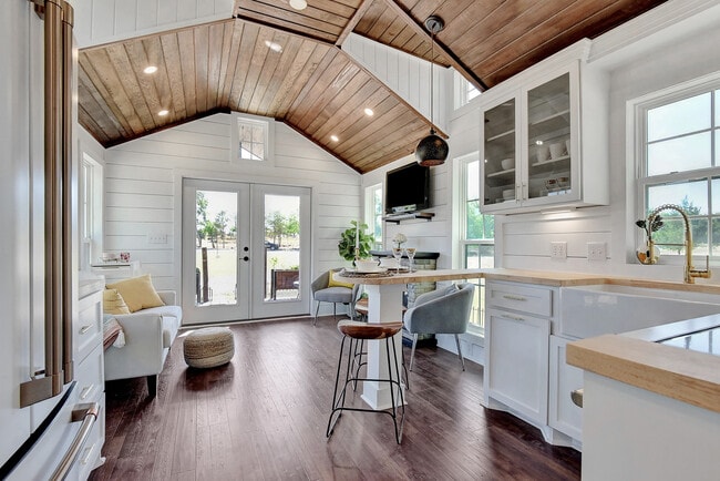 Interior con revestimiento de madera machihembrada, techo alto de madera y puertas francesas que dan a la terraza delantera. - 2510 Private Road 1180