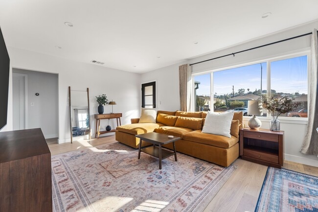 Living room with West Elm furniture, natural sunlight, and large TV flatscreen.