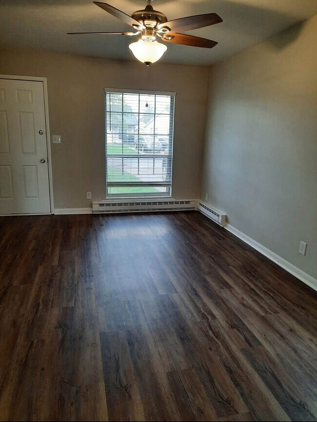 Inviting living room with elegant wood flooring, large window for natural light, and modern ceiling fan.