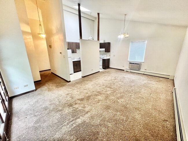 Acogedora sala de estar de concepto abierto con lujosas alfombras, abundante luz natural y un acogedor rincón de cocina perfecto para una vida moderna y cómoda.