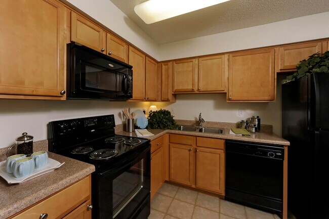 Classic Package II kitchen with oak cabinetry, beige laminate countertops, black appliances and tile flooring