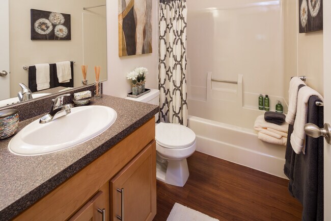 Classic Package bathroom with black speckled laminate countertops, maple cabinetry and hard surface flooring