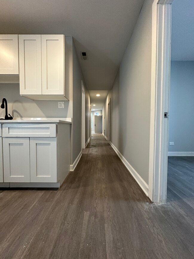 Renovated kitchen with white cabinetry and a view down the hallway - 5653 S May St Unit 1