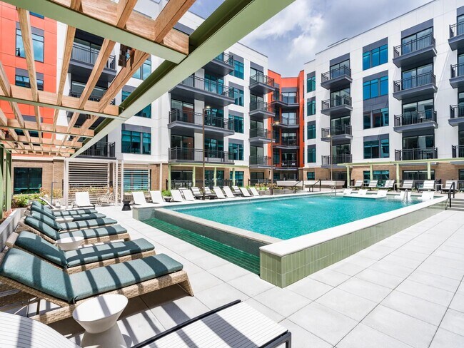 Resort-style pool with in-water loungers, shaded seating, and a spacious sundeck for warm-weather relaxing. - Modera SoBro Rental