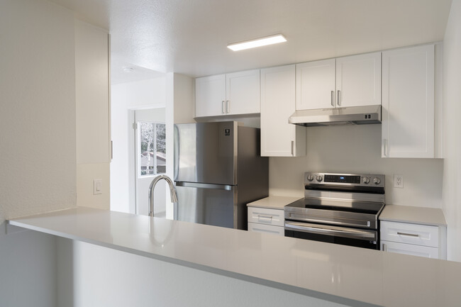 Renovated Package I kitchen with stainless steel appliances, light grey quartz countertops, and new white cabinetry - eaves Mission Viejo Apartments