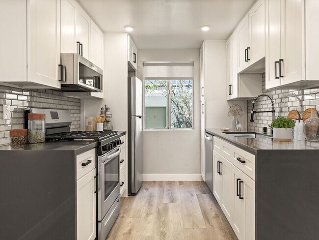 Tiled kitchen with stainless steel microwave, oven, fridge, and fixtures.