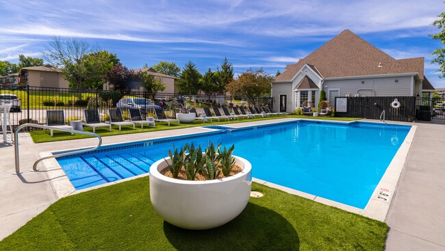 Relax and unwind at our serene poolside area, featuring comfortable lounge chairs, lush greenery, and a tranquil atmosphere perfect for a refreshing swim or sunbathing. - Market 1900 Apartment Homes