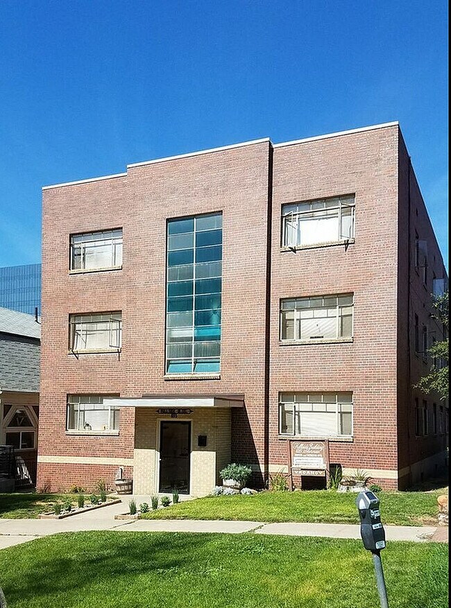 Elegante edificio de apartamentos de ladrillo con grandes ventanales y un césped bien cuidado.