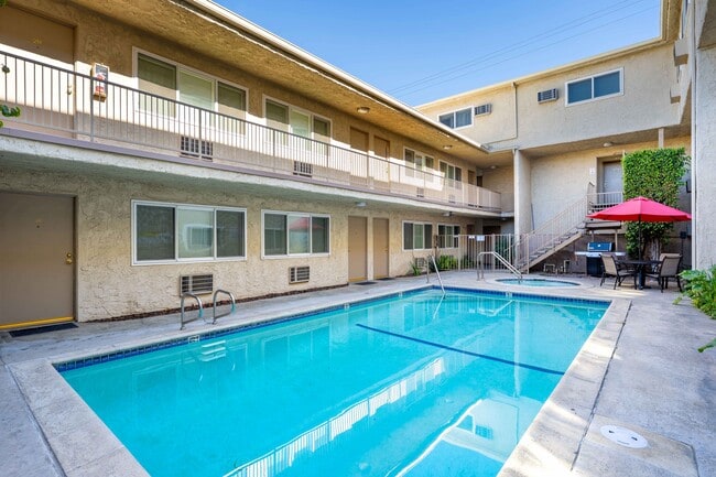 A central courtyard at the Esplanade featuring a sparkling swimming pool, hot tub, and poolside seating area.