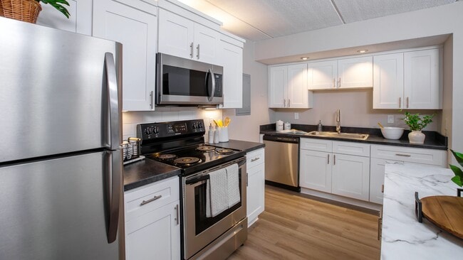 Discover the sleek and functional design of our modern kitchens, featuring stainless steel appliances, black granite-style countertops, and chic white cabinetry, offering the perfect balance of style and efficiency. - Elon Winter Park Apartments