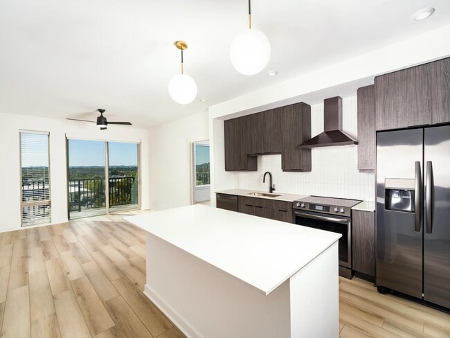 An open kitchen at Modera Nations in Nashville features a spacious island and the choice of light or dark finishes, with skyline views extending the living space.