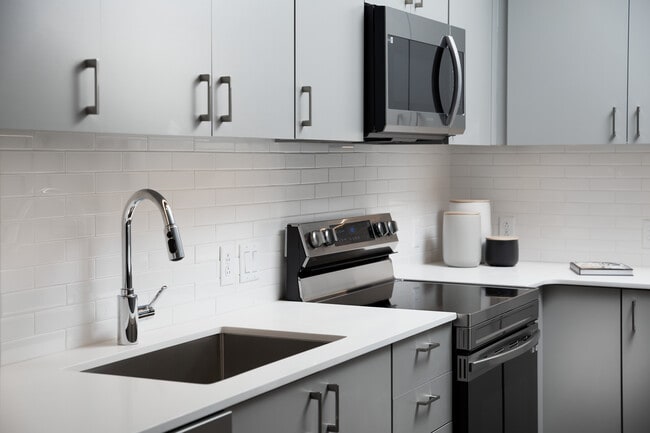 Modern kitchens with light grey cabinetry, white quartz countertops, and stainless steel appliances - Avalon Brighton Apartments