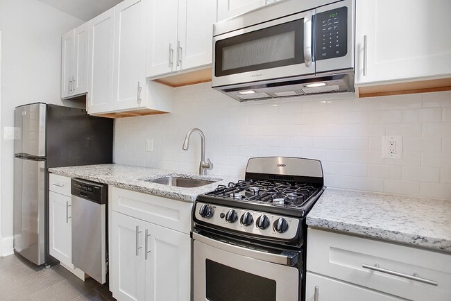 Renovated kitchen with granite countertops and stainless steel appliances - President Madison Apartments