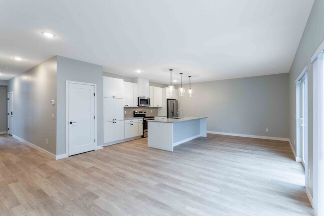 Modern open-concept kitchen with sleek cabinetry, stainless steel appliances, and elegant pendant lighting over a spacious island, perfect for entertaining.