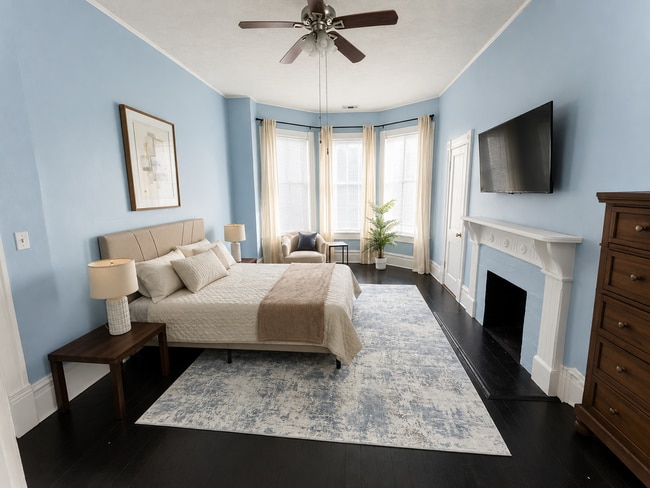 Spacious furnished bedroom with queen bed and bay windows