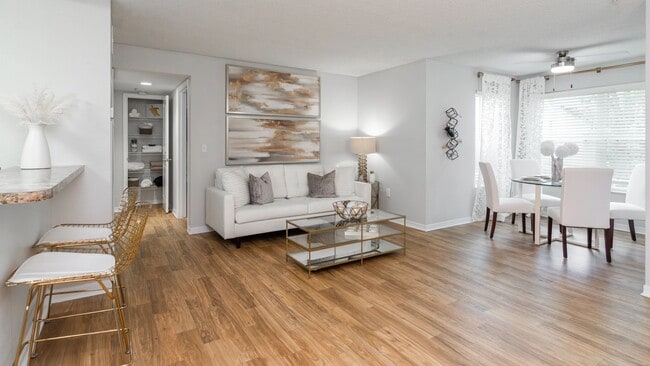 This open-concept layout features a cozy living room, sunlit dining nook, and a stylish breakfast bar. - Ashton Chase