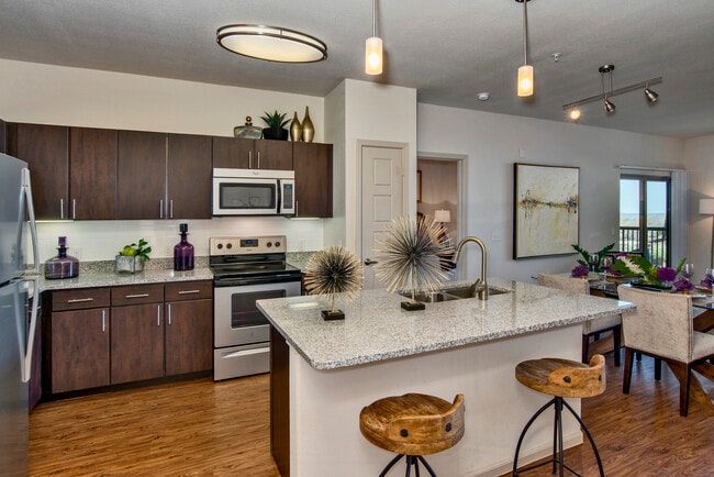 Classic Package I kitchen with espresso cabinetry, speckled granite countertops, white subway tile backsplash, stainless steel appliances, and hard surface flooring
