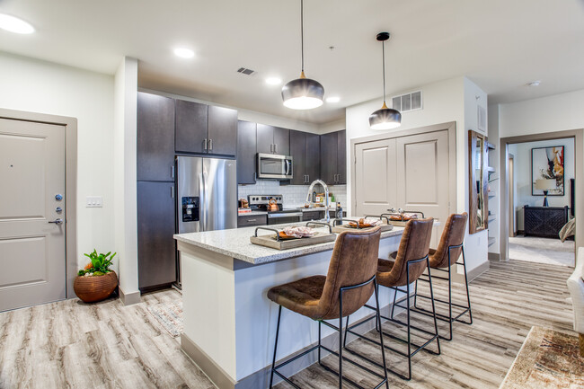 Kitchen with espresso cabinetry, speckled granite countertops, white subway tile backsplash, stainless steel appliances, and hard surface flooring - Avalon Benbrook Apartments