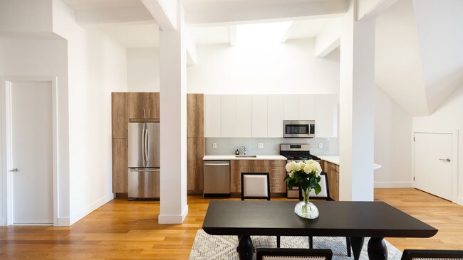 photo of 95 Horatio St Model Apt 702 Open Kitchen with stainless steel appliances, staged with dining set - The West Coast