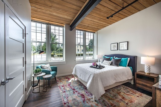 Spacious Bedroom With Large Windows, Exposed Beam Ceiling And Wood Plank Floors. - Sterling Lofts, A 55+ Community
