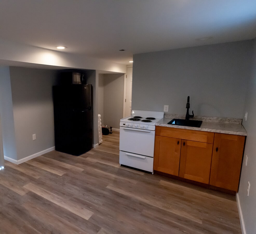 Kitchen includes over-the-counter cabinets and ducted range hood over stove. - 1000 Charles St Unit Basement Apartment
