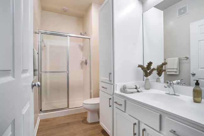 Renovated Package II bath with white countertops, white cabinetry, and hard surface flooring