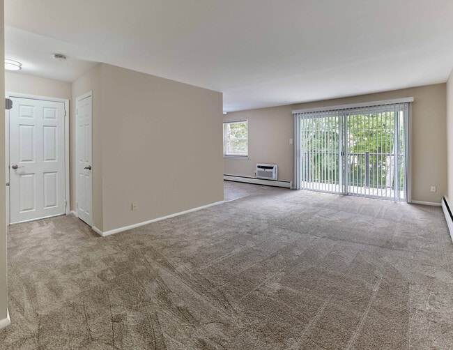 Expansive living area with wall-to-wall carpet and private balcony at Maple Terrace Apartments in Maple Shade, NJ